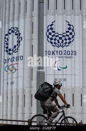 (210721) -- TOKIO, 21. Juli 2021 (Xinhua) -- EIN Radfahrer kommt am Logo von Tokyo 2020 in der Innenstadt von Tokio, Japan, 21. Juli 2021 vorbei. Die Olympischen Spiele 2020 in Tokio beginnen hier am Freitag. (Xinhua/Liu Dawei) Stockfoto