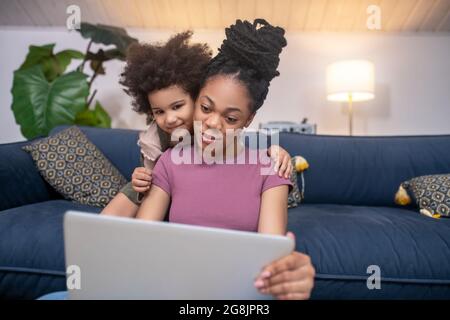 Lächelnde Mutter mit Tochter, die auf den Laptop-Bildschirm schaut Stockfoto