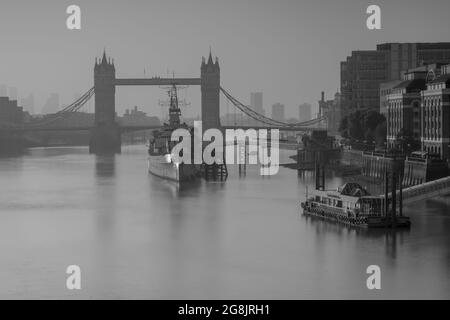 City of London, Großbritannien. Juli 2021. Wetter in Großbritannien: Wunderschöner, trüber Sonnenaufgang über der Tower Bridge, der City of London und der HMS Belfast, als die Hauptstadt während der Hitzewelle zu einem weiteren Tag mit herrlichem Sonnenschein und klarem Himmel aufwacht. Kredit: Celia McMahon/Alamy Live Nachrichten Stockfoto