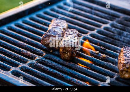 Nahaufnahme von Fleischbrötchen, die Mici oder mititei genannt werden, auf einem Brazier mit brennendem Feuer und Rauch Stockfoto