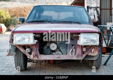 Vorderansicht eines alten verlassenen Wagens mit fehlenden Teilen auf dem Schrottplatz. Stockfoto