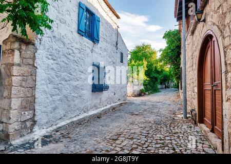 Historische Steinhäuser und eine gepflasterte Straße in Alacati, Cesme, Izmir, Türkei. Stockfoto