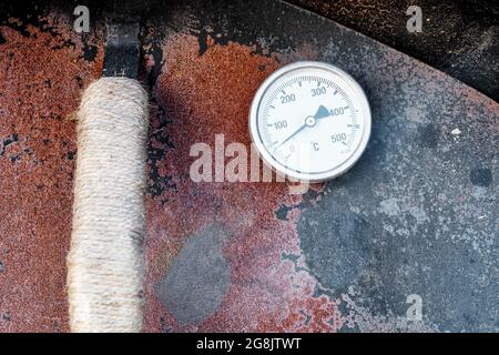 Rostige Metalltür eines Steinofens mit Thermometer. Detailansicht aus nächster Nähe. Stockfoto