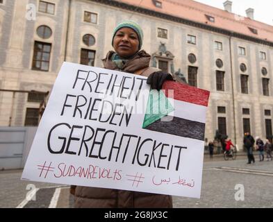 Frau mit Schild mit der Aufschrift Freiheit Frieden Gerechtigkeit Sudan Revelts. Zwei Dutzend Sudanesen und Sudanesen haben sich in München zusammengefunden, um Solidarität mit den Protesten im Sudan zu zeigen. The Prothest reciprod are goes to the Machthaber Umar al-Bashir. (Foto: Alexander Pohl/Sipa USA) Quelle: SIPA USA/Alamy Live News Stockfoto