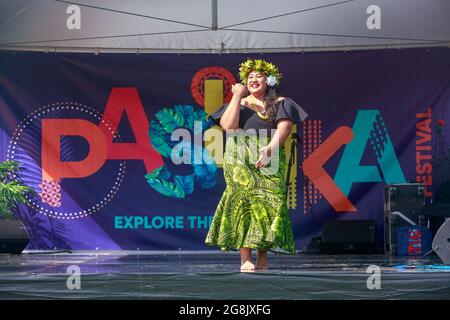 Eine polynesische Frau, die vor dem Logo zum Pasifika Festival tanzt, einer Feier der Kultur der Pazifikinsel in Auckland, Neuseeland Stockfoto