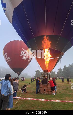 Heißluftballons, einer davon wird von einem Flammenausbruch aus einem Brenner aufgeblasen, beim „Balloon over Waikato“-Festival in Hamilton, Neuseeland Stockfoto