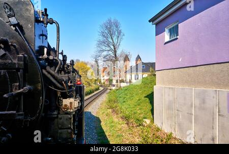 Hauswand mit einer vorbeifahrenden Dampflokomotive. Dynamisch durch Bewegungsunschärfe. Stockfoto