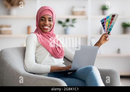 Muslimische Frauenjobs. Schwarze Islamische Designerin Mit Laptop Und Farbmustern Stockfoto