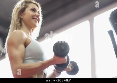 Brutal athletische Frau pumpt Muskeln mit Hanteln Stockfoto