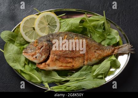 Gebratener Fisch dorado mit frischen Kräutern und Zitrone auf silbernem Tablett Stockfoto