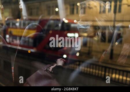 Blonde Frau mit Gesichtsmaske, die sich in der Nacht im Busfenster widerspiegelt, London, 21. Februar 2021 Stockfoto