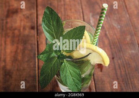 Sommerzitruscocktail Mojito mit Zitrone und Minze. Kalte Limonade mit Zitrone auf einem braunen Holztisch. Stockfoto