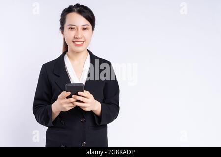Junge vietnamesische Mitarbeiterin in schwarzem Anzug mit Mobiltelefon und lächelnd Stockfoto