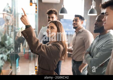 Kollegen führen Brainstorming mit klebrigen Post-it-Notizen an der Glaswand durch Stockfoto