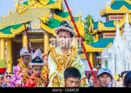 Der Junge wird für seine Novizierungszeremonie für Shinbyu-Novizen in der Shwedagon Pagode, Yangon (Rangun), Myanmar (Burma) getragen Stockfoto