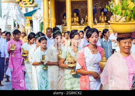 Burmesische Mädchen, die elegant mit Opfergaben gekleidet sind, nehmen an einer Noviziationszeremonie (Shinbyu) in der Shwedagon Pagode, Yangon, Myanmar, Teil Stockfoto