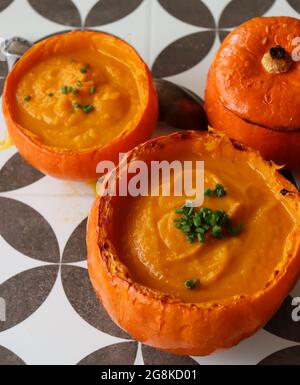 Butternut-Squashsuppe in einer Squashschale. Cremige Herbstsuppe mit Butternut und Karotten in Kürbisschüssel. Gesunde Ernährung Konzept. Gemütliches Herbstessen Stockfoto