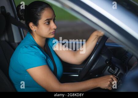 Junge hispanische Hündin in einem blauen T-Shirt, die das Auto startet Stockfoto