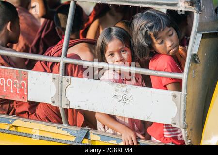 Niedliches junges burmesisches Mädchen mit Thanaka-Puder, das aus dem Fenster des örtlichen Busses in Bagan, Myanmar, blickt Stockfoto