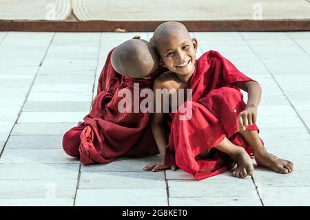 Zwei junge buddhistische Novizen aus Burma, die auf dem Boden saßen und sich für Fotos herumdummten, Monywa, Myanmar Stockfoto