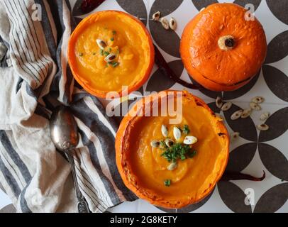 Curry Butternut-Kürbissuppe mit Kokosmilch. Vegane Kürbissuppe in einer Squashschale. Essen gesunde Konzept. Stockfoto