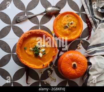 Butternut-Squashsuppe in einer Squashschale. Cremige Herbstsuppe mit Butternut und Karotten in Kürbisschüssel. Gesunde Ernährung Konzept. Gemütliches Herbstessen Stockfoto