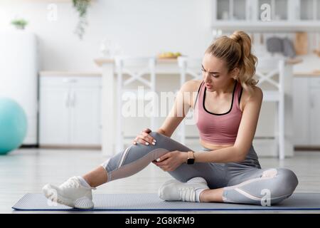 Trainingsverletzung zu Hause. Frau, die nach dem Training zu Hause Schmerzen spürt Stockfoto