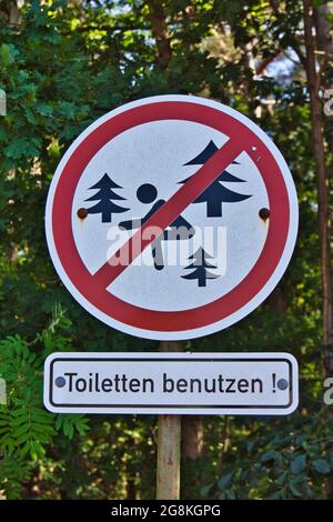 Vertikale Aufnahme eines Wegweisses mit der Aufschrift „Toilette benutzen“ - Verbot der Nutzung des Waldes als Toilette Stockfoto