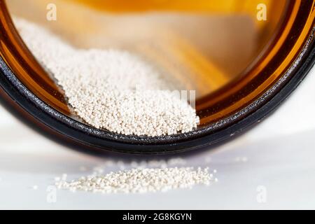 Schnell aufsteigende Hefe, die aus dem Glas ausläuft. Kleine körnige oder gefräste Partikel aus Instant Hefe für Brot und Backen im Vorratsbehälter. Selektiver Fokus bei Stockfoto