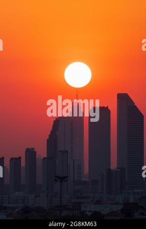 Luftaufnahme der Skyline von Bangkok bei Sonnenuntergang, glühende Sonne unter dem Geschäftsviertel. Thailand. Konzentrieren Sie sich auf die Sonne. Stockfoto