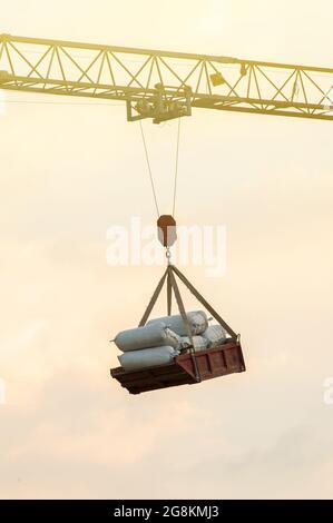 Ein alter Hammerhead-Kran, der auf einer Baustelle Zementsäcke hebt, Himmel im Hintergrund. Stockfoto