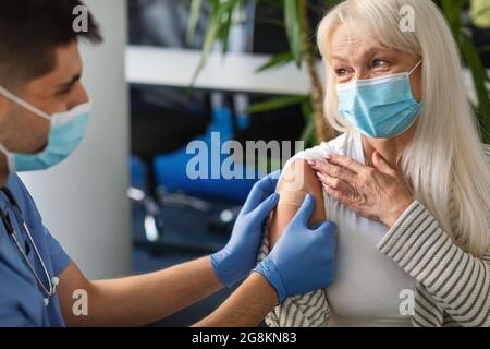 Reife Frau, Die Gegen Covid-19 Geimpft Wird, Arzt, Der Gips Anwendet Stockfoto