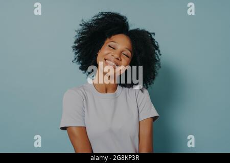 Porträt einer fröhlichen jungen Frau mit afro Frisur isoliert über pastellblauen Studio-Hintergrund Stockfoto