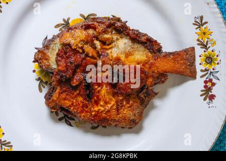 Ein gebratener Pomfret-Fisch, serviert auf einer weiß dekorierten Platte, würzige indische Gerichte. Pomfrets sind Perciforme, die zur Familie Bramidae gehören. Stockfoto