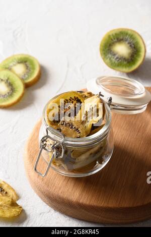 Früchte Kiwi-Chips im Glas auf hellem Hintergrund, Heimtrocknung. Vegane, zuckerfreie Lebensmittel. Nahaufnahme Stockfoto