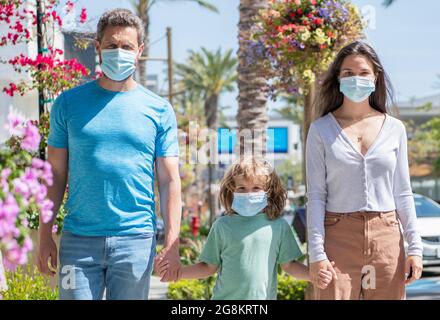 Junge Familie von Mutter Vater und Sohn tragen Schutzmaske zu Fuß im Freien, covid Stockfoto