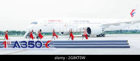 Tianjin. Juli 2021. Eine Band tritt vor einem Airbus A350-Flugzeug auf, das an China Eastern Airlines im Airbus Tianjin Widebody Completion and Delivery Center im nordchinesischen Tianjin ausgeliefert wurde, 21. Juli 2021. Airbus hat sein A350-Flugzeugprojekt in seinem Großraumfertigungs- und Auslieferungszentrum im nordchinesischen Tianjin eingeweiht. Es ist das erste Mal, dass der europäische Flugzeugbauer ein solches Projekt für den A350 außerhalb Europas lanciert hat. Quelle: Zhang Yuwei/Xinhua/Alamy Live News Stockfoto