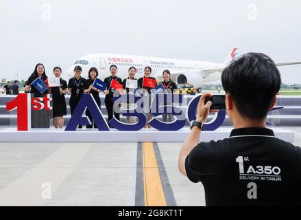 Tianjin. Juli 2021. Mitarbeiter posieren für ein Gruppenfoto vor einem Airbus A350-Flugzeug, das an China Eastern Airlines im Airbus Tianjin Widebody Completion and Delivery Center im nordchinesischen Tianjin ausgeliefert wurde, 21. Juli 2021. Airbus hat sein A350-Flugzeugprojekt in seinem Großraumfertigungs- und Auslieferungszentrum im nordchinesischen Tianjin eingeweiht. Es ist das erste Mal, dass der europäische Flugzeugbauer ein solches Projekt für den A350 außerhalb Europas lanciert hat. Quelle: Zhang Yuwei/Xinhua/Alamy Live News Stockfoto