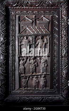 Rom Colle Aventino, Basilika Santa Sabina .insbesondere das große geschnitzte Zypressenportal, das aus dem 5. Jahrhundert stammt und perfekt erhalten ist, das erste Beispiel der christlichen Holzskulptur. Die achtzehn Tafeln, aus denen sie besteht, sind wirklich außergewöhnlich und stellen Szenen aus dem Alten und Neuen Testament dar. Man kann deutlich sehen, wie zwei verschiedene Künstler in der Tür arbeiten, einer ist klassizistischer mit einem hellenistischen Stempel, der andere hat Darstellungen von Volkskunst geschnitzt, darunter das erste erhaltene Bild von Christus, der zwischen den beiden Dieben gekreuzigt wurde. Geht und sucht die Szene des Durchgangs von Stockfoto