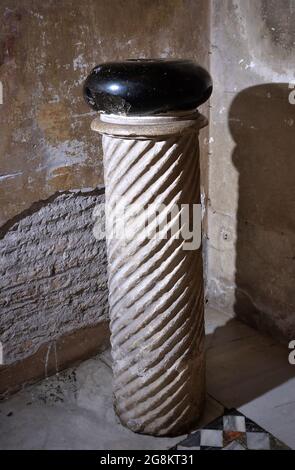 Rom Colle Aventino, Basilika Santa Sabina. Der Stein des Teufels. Links von der Eingangstür befindet sich eine gedrehte Säule, mit einem glänzenden und runden schwarzen Stein auf der Oberseite, mit Löchern, die aussehen, wie die, um Ihre Finger auf Bowlingkugeln legen, Was jeder den 'lapis diaboli', den Stein des Teufels, nennt. Die Legende besagt, dass der Teufel den Stein griff (daher die Fußabdrücke) und warf ihn auf St. Dominic, der auf dem Grabstein der Knochen der Proto-Märtyrer bete, ihn vermisste und die Platte zerbrach (die tatsächlich beschädigt wurde und während der Arbeiten ersetzt wurde. Sechzehnten Jahrhundert und dann wiederentdeckt Stockfoto