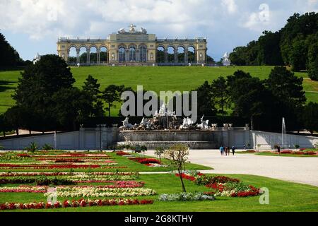 Wien, Österreich - Blick vom Schloss Schönbrunn in Richtung Neptunbrunnen und Gloriette über herrliche Blumen und Parkanlagen Stockfoto