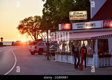 Herrlicher goldener Sonnenuntergang, der im Gelände reflektiert wird, mit Touristen, die zu Wilson's Ice Cream Parlor, gegründet 1906, Ephraim, Door County, Wisconsin, USA Stockfoto