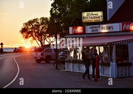 Herrlicher goldener Sonnenuntergang, der im Gelände reflektiert wird, mit Touristen, die zu Wilson's Ice Cream Parlor, gegründet 1906, Ephraim, Door County, Wisconsin, USA Stockfoto