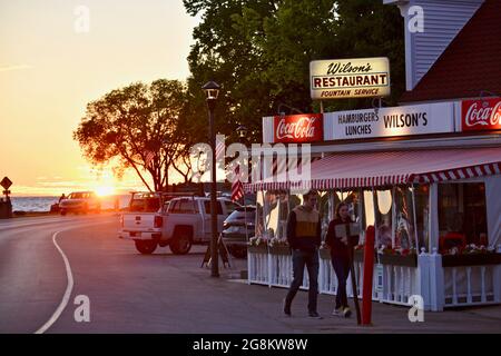 Herrlicher goldener Sonnenuntergang, der im Gelände reflektiert wird, mit Touristen, die zu Wilson's Ice Cream Parlor, gegründet 1906, Ephraim, Door County, Wisconsin, USA Stockfoto