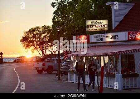 Herrlicher goldener Sonnenuntergang, der im Gelände reflektiert wird, mit Touristen, die zu Wilson's Ice Cream Parlor, gegründet 1906, Ephraim, Door County, Wisconsin, USA Stockfoto