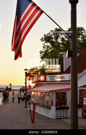 Herrlicher goldener Sonnenuntergang, der im Gelände reflektiert wird, mit Touristen, die zu Wilson's Ice Cream Parlor, gegründet 1906, Ephraim, Door County, Wisconsin, USA Stockfoto