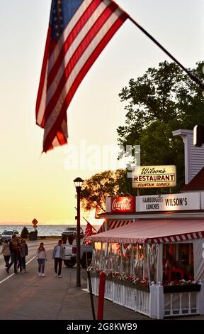 Herrlicher goldener Sonnenuntergang, der im Gelände reflektiert wird, mit Touristen, die zu Wilson's Ice Cream Parlor, gegründet 1906, Ephraim, Door County, Wisconsin, USA Stockfoto