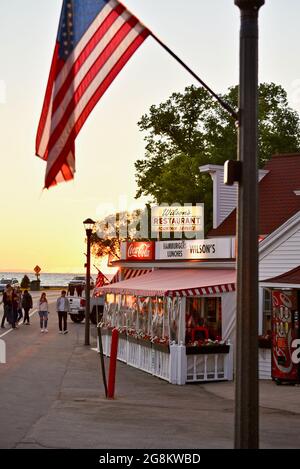 Herrlicher goldener Sonnenuntergang, der im Gelände reflektiert wird, mit Touristen, die zu Wilson's Ice Cream Parlor, gegründet 1906, Ephraim, Door County, Wisconsin, USA Stockfoto