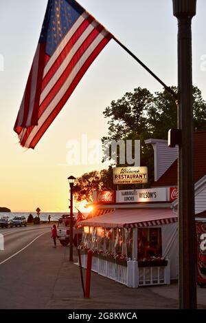 Herrlicher goldener Sonnenuntergang, der im Gelände reflektiert wird, mit Touristen, die zu Wilson's Ice Cream Parlor, gegründet 1906, Ephraim, Door County, Wisconsin, USA Stockfoto