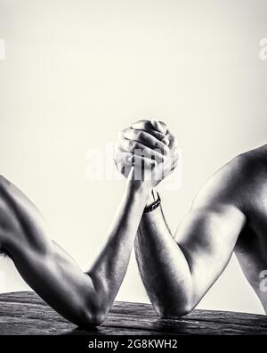 Armdrücken. Stark muskulös bärtiger Mann, der einen schwach schwachen Mann am Arm kämpft. Schwarz und Weiß Stockfoto